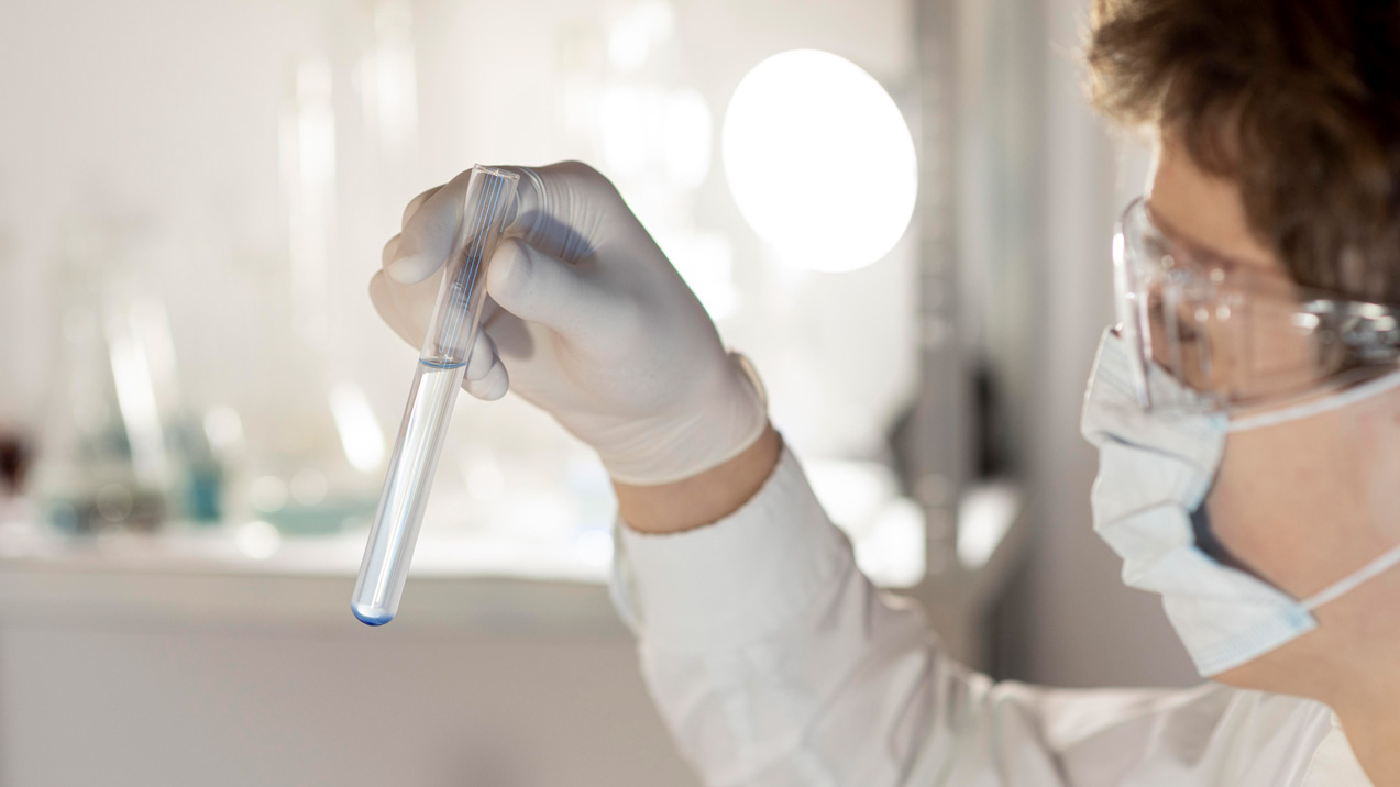 Laborant w laboratorium środowiskowym trzymający próbówkę z próbką do analizy jonowej i spaleniowej
